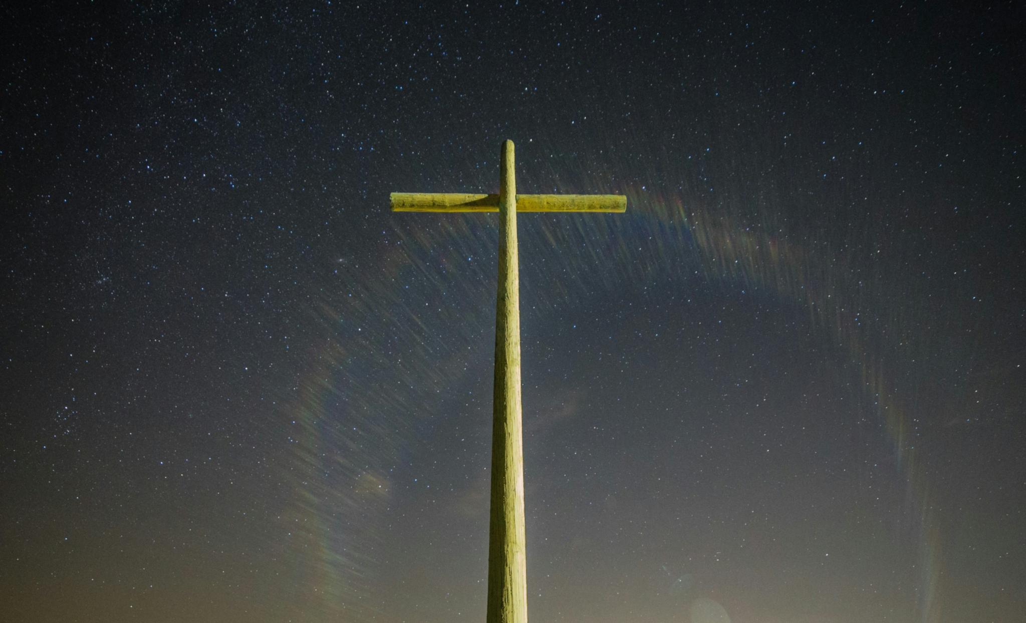 Goldenes Kreuz vor dunklem Himmel mit Sternen