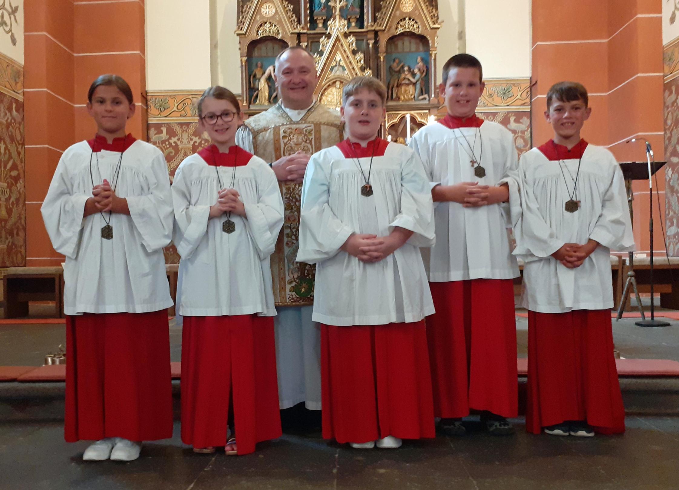 Das Foto zeigt die neuen Messdienerrinnen und Messdiener sowie Kooperator Konrad Lisowski vor dem Hochaltar in der Kirche St. Lubentius in Kobern